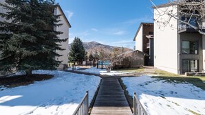 A snow-covered pathway leading to a building with a mountain in the background. - ⭐️ LARGE DECK + FIREPLACE ⎮ Hot Tubs- Walk to Mtn ⎮ (Steamboat Springs)