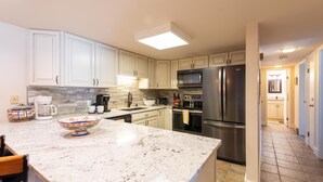 A modern kitchen with white cabinets, a granite countertop, a stainless steel refrigerator, and a microwave. - ⭐️ LARGE DECK + FIREPLACE ⎮ Hot Tubs- Walk to Mtn ⎮ (Steamboat Springs)