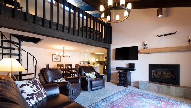 A spacious living area with a staircase, leather sofas, a large rug, and a fireplace. - ⭐️ LARGE DECK + FIREPLACE ⎮ Hot Tubs- Walk to Mtn ⎮ (Steamboat Springs)