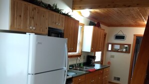 Una cocina con armarios de madera, un refrigerador blanco y un lavabo.