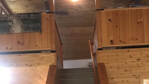 Una escalera de madera en una cabaña, con una zona de cocina a cada lado.