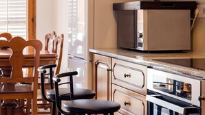 A kitchen with wooden cabinets, a microwave, and a stove. There are two stools and a dining table with chairs. - Beach Apartment in Calella, Barcelona. Free Wifi, a / c (Calella)