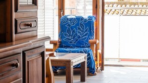 A room with a wooden cabinet, a blue chair with a floral pattern, and a wooden table. - Beach Apartment in Calella, Barcelona. Free Wifi, a / c (Calella)