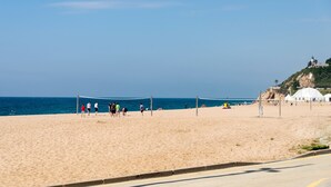 A beach volleyball court with players, a clear sky, and a coastal view. - Beach Apartment in Calella, Barcelona. Free Wifi, a / c (Calella)