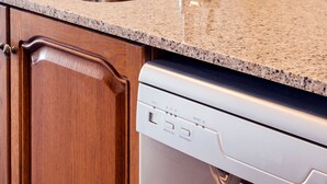 A kitchen with a stainless steel sink, granite countertop, wooden cabinets, and a built-in dishwasher. - Beach Apartment in Calella, Barcelona. Free Wifi, a / c (Calella)