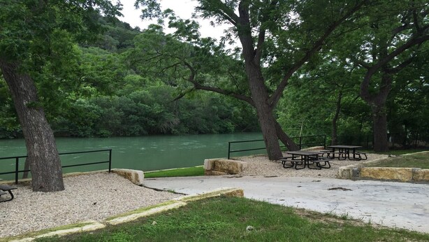 A riverside park with picnic tables and benches. - Escape the heat and cool off this summer in the Guadalupe! (New Braunfels)