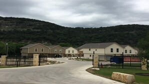 A residential area with houses, a paved driveway, and a stone fence. - Escape the heat and cool off this summer in the Guadalupe! (New Braunfels)