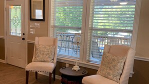 A room with two armchairs, a small round table, and a door with a stained glass window. - Escape the heat and cool off this summer in the Guadalupe! (New Braunfels)