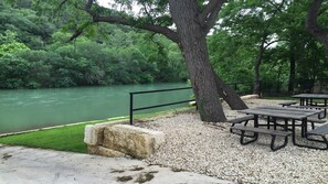 Un espacio para picnic junto al río, con bancos y un sendero de hormigón.