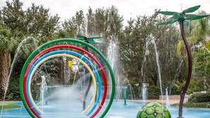 Ein Wasserpark mit einer bunten, kreisförmigen Wassersp installations und einer grünen Schildkröten-ähnlichen Struktur.