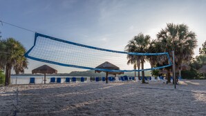 Ein Beachvolleyballnetz vor Palmen und Strandliegen.