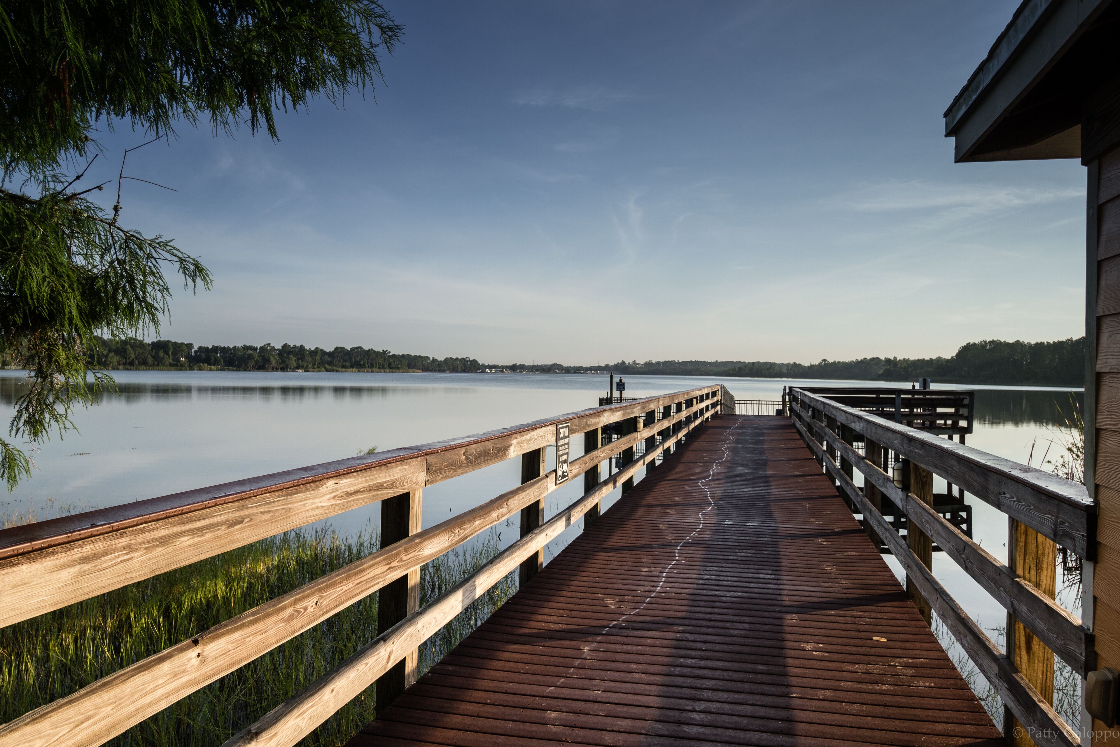 Un muelle de madera que se extiende sobre aguas tranquilas, bajo un cielo despejado.