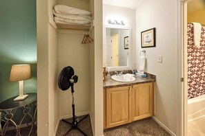 Une salle de bain équipée d’un lavabo, d’un miroir, d’un porte-serviettes et d’un ventilateur.
