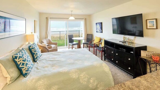 Habitación de hotel con una cama grande, televisión, escritorio y balcón con vistas.