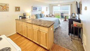 Habitación de hotel compacta con kitchenette, una cama con vistas, zona de comedor y televisor.