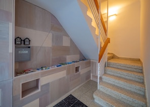 A modern staircase with a wooden handrail and a check-out machine on the wall.