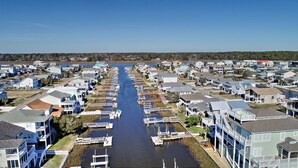 Une zone résidentielle côtière, avec des maisons le long d’un étroit canal, des quais et un ciel dégagé.