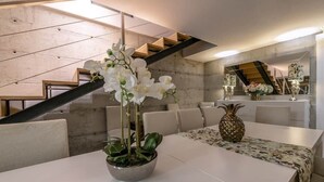 A modern dining area with a white table, a potted plant, and a pineapple centerpiece. - Longra Family Villa & SPA (Mirandela)