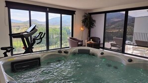 A hot tub with a view of mountains, a treadmill, and a balcony with chairs. - Longra Family Villa & SPA (Mirandela)