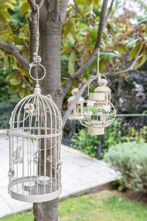 Two white birdcages hanging from a tree. - Villa Nina (Penteli)