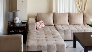 A modern living room with a sectional sofa, a small table, and a glass coffee table. - Villa Nina (Penteli)