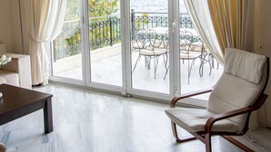 A spacious living area with a balcony, a dining table, and a lounge chair. - Villa Nina (Penteli)