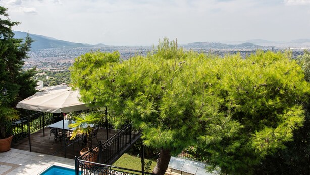 A patio with a pool, outdoor furniture, and a view of a cityscape and mountains. - Villa Nina (Penteli)