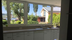 A kitchen with a large window, white cabinets, and a stainless steel sink. - Apartment Anker am See (Wangen)