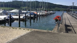 A marina with boats docked, a wooden walkway, and a backdrop of hills. - Apartment Anker am See (Wangen)
