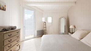 A bedroom with a bed, dresser, mirror, and a door leading to a balcony.
