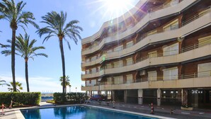 A hotel with a swimming pool, palm trees, and a view of the ocean. - SOL DE ESPAÑA Apartments - Beachfront (Cambrils)