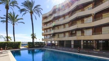 A hotel with a swimming pool, palm trees, and a view of the ocean.