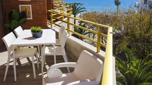 A terrace with a table and chairs, a potted plant, and a view of the sea. - SOL DE ESPAÑA Apartments - Beachfront (Cambrils)