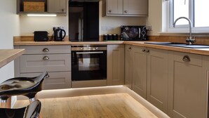 A modern kitchen with a built-in oven, microwave, and stainless steel range hood.