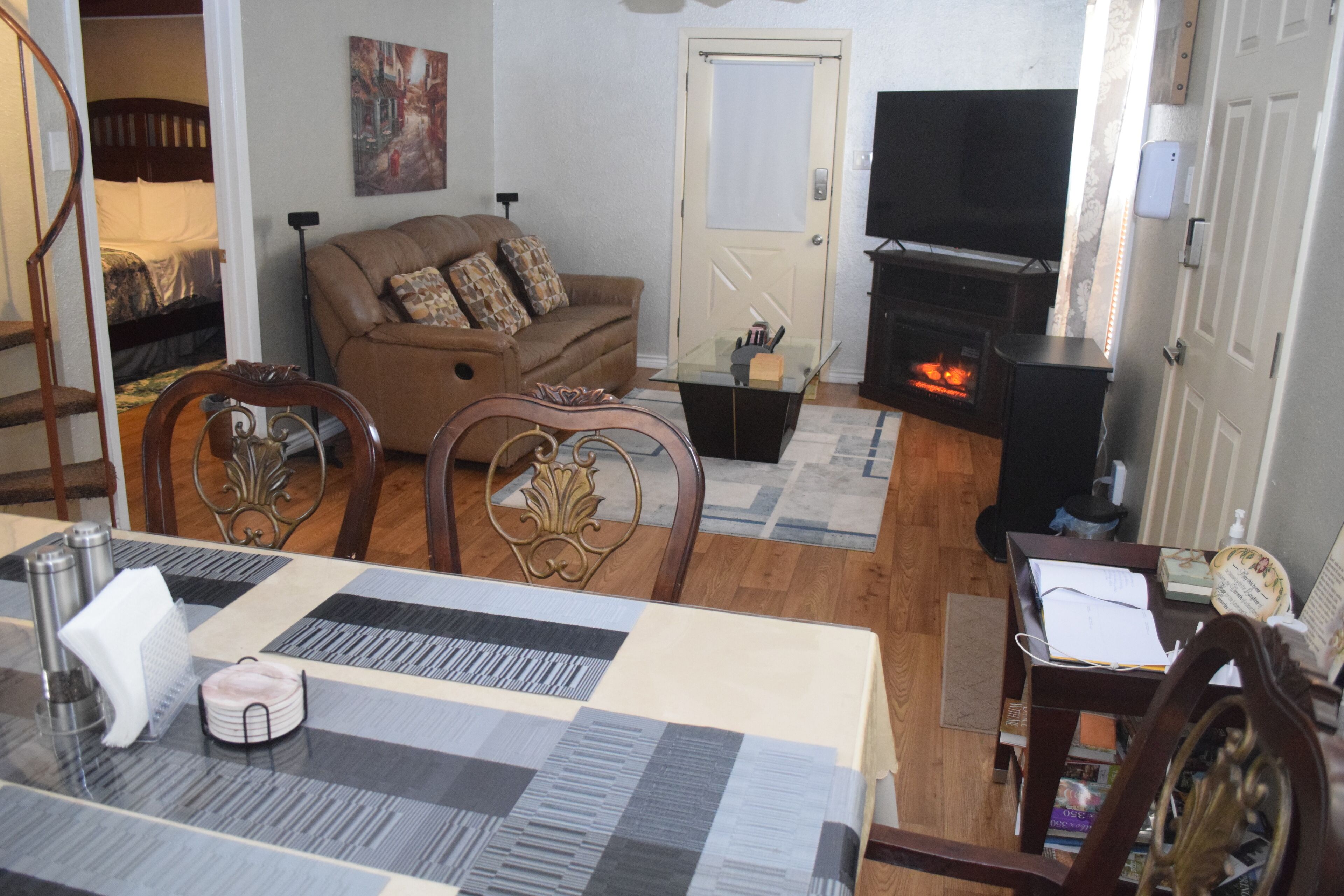 Ein Wohnzimmer mit einer Couch, einem Kamin, einem Fernseher und einem Essbereich mit Tisch und Stühlen.