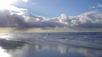 Een strand met golven en een gedeeltelijk bewolkte lucht.