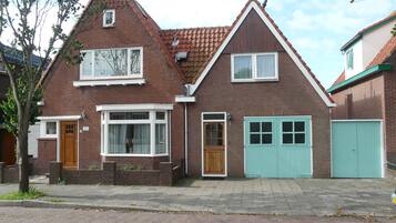 Een herenhuis met een bakstenen gevel, een schilddak en een garage.