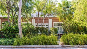 A building with a brick facade, surrounded by lush greenery and trees. - Hemingway Hideaway in the Truman Annex (Key West)