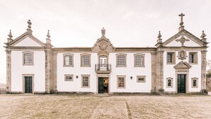 A historic building with a symmetrical facade, multiple windows, and a central entrance with a balcony. - Solar das Bouças (Amares)