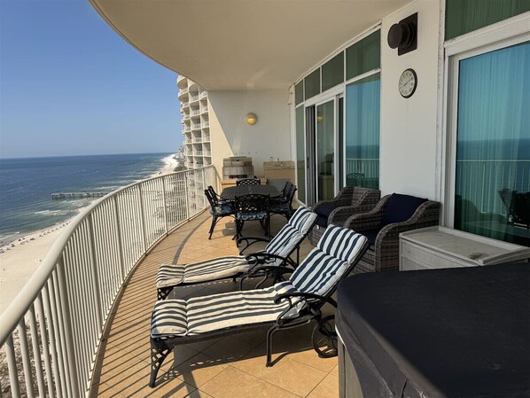 A balcony with two striped lounge chairs, a table, and a sofa.