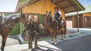 A wooden building with a green awning and a covered porch. - Camping Fort Bravo (Tabernas)