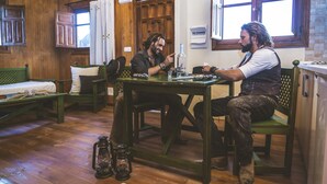 A rustic wooden room with a bed, a table, and a chair. - Camping Fort Bravo (Tabernas)