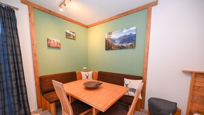 A corner room with a wooden table and benches, green walls, and two framed pictures.