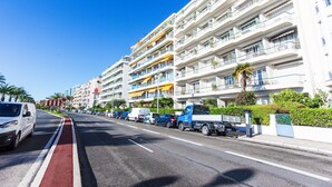 A multi-story hotel with balconies, a red bike lane, and parked vehicles along the street.