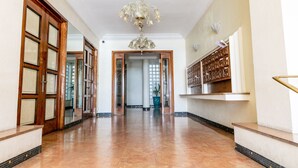 A spacious hallway with a polished floor, a chandelier, and a wall-mounted shelf with storage boxes.