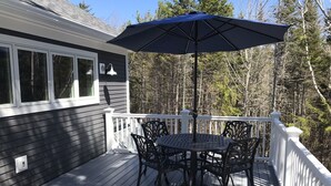 En terrass med ett bord och stolar, ett blått parasoll och ett räcke.