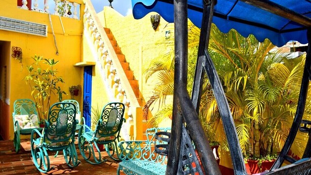 A courtyard with a staircase, metal chairs, and potted plants. - Hostal Casa Azul Santa Ana TRINIDAD (Trinidad)