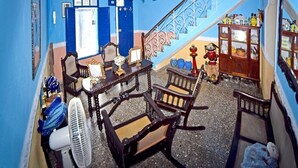 A room with a staircase, wooden furniture, a fan, and a cabinet with glass doors. - Hostal Casa Azul Santa Ana TRINIDAD (Trinidad)