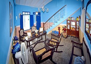 Una habitación con una escalera, muebles de madera, un ventilador y un aparador con puertas de cristal.