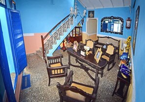 Una habitación con una escalera, muebles de madera, un ventilador y un cartel que dice 'BIENVENIDO'.